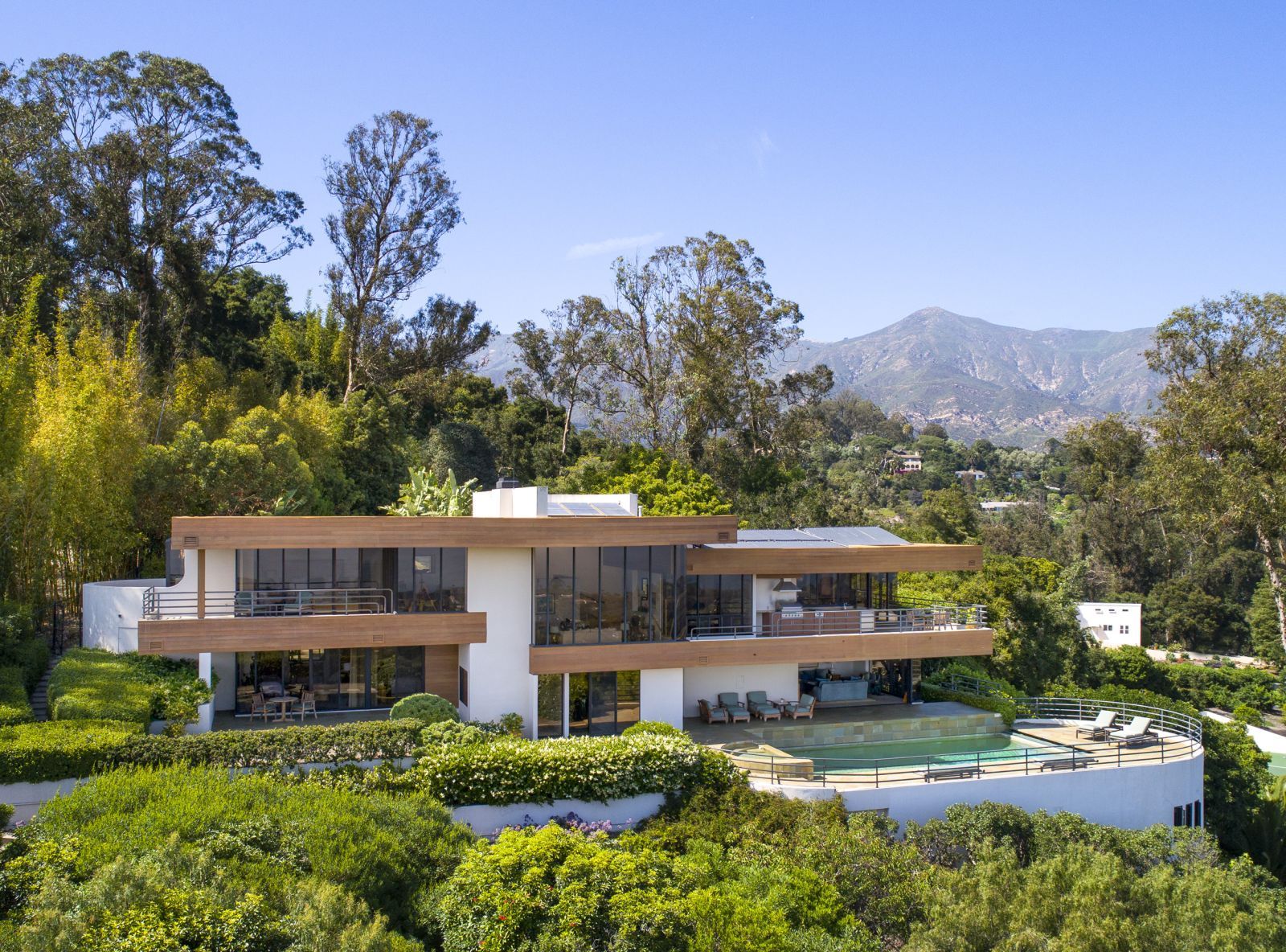 A luxury contemporary home in Montecito surrounded by lush vegetation with mountains in the background